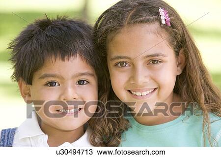 Stock Image - Brother and sister outdoors smiling. Fotosearch