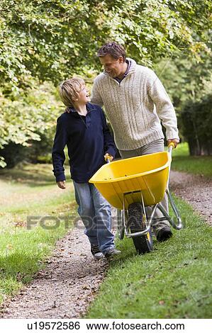 Father and son walking on path pushing wheelbarrow View Large Photo Image Stock Photograph - Father and son walking on path pushing wheelbarrow. Fotosearch