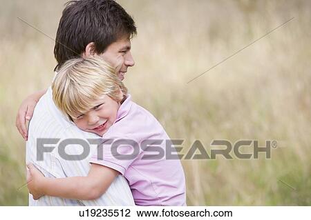 Father holding son outdoors smiling View Large Photo Image Stock Image - Father holding son outdoors smiling. Fotosearch