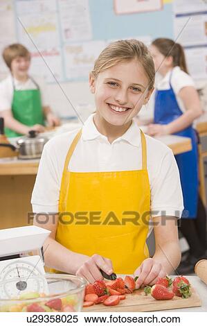 Stock Photography - Female student slicing berries in cooking class. Fotosearch