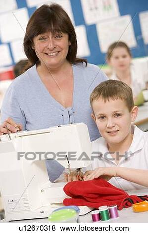 Stock Photo - Male student using sewing machine with teacher. Fotosearch