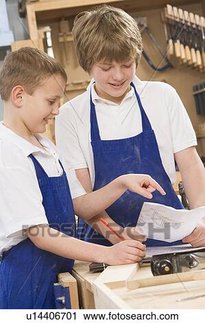 Stock Image - Male students reviewing woodworking plans. Fotosearch