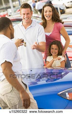 Stock Image - Mother and father with young daughter shopping for a new car. Fotosearch