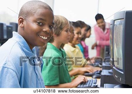 Stock Photo - Six children at computer terminals with teacher in background (depth of field/high key). Fotosearch