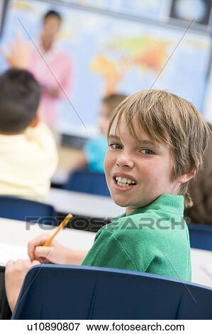 Student in class looking at camera with teacher in background (selective focus) View Large Photo Image Stock Photo - Student in class looking at camera with teacher in background (selective focus). Fotosearch
