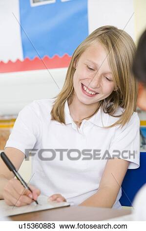 Stock Image - Student in class taking notes. Fotosearch