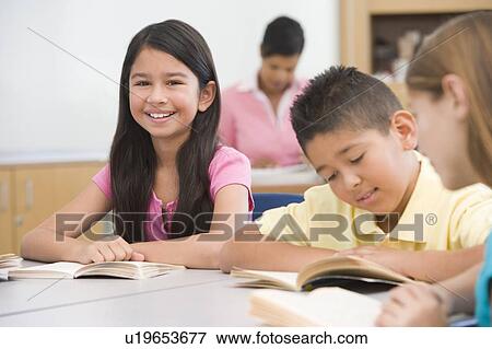 Students in class reading with teacher in background (selective focus) View Large Photo Image Stock Photo - Students in class reading with teacher in background (selective focus). Fotosearch