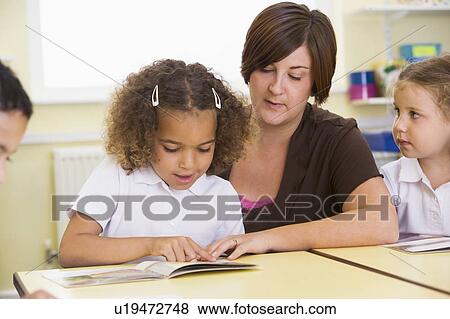 Stock Photo - Students in class with teacher reading (selective focus). Fotosearch