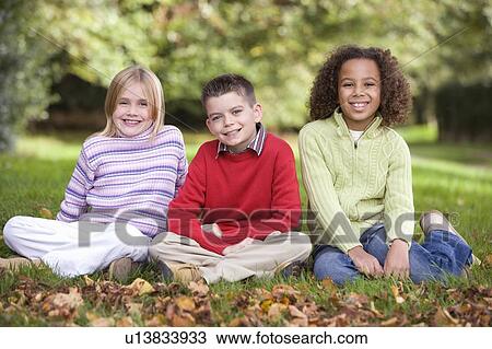 Three young children sitting outdoors smiling (selective focus) View Large Photo Image Stock Image - Three young children sitting outdoors smiling (selective focus). Fotosearch