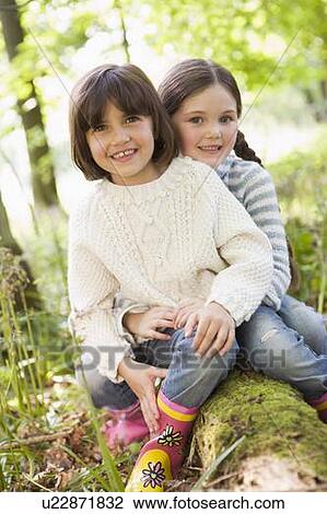 Two sisters outdoors in woods sitting on log smiling View Large Photo Image Stock Image - Two sisters outdoors in woods sitting on log smiling. Fotosearch