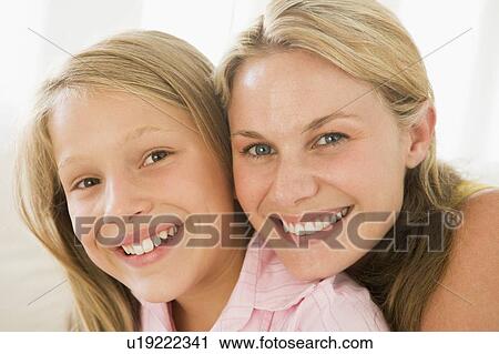 Stock Image - Woman and young girl in living room smiling. Fotosearch