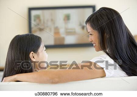 Stock Photograph - Woman and young girl in living room with flat screen television smiling. Fotosearch
