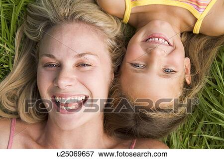 Stock Photo - Woman and young girl lying in grass laughing. Fotosearch