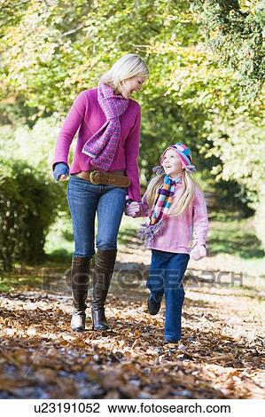 Stock Image - Woman and young girl walking outdoors in park and smiling. Fotosearch