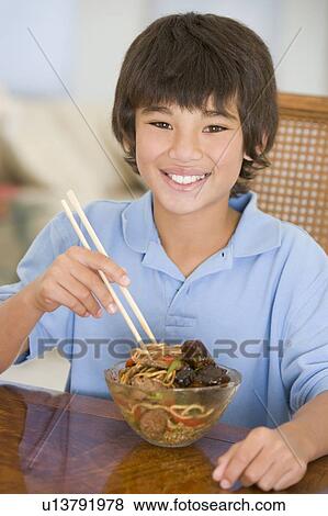 Young boy in dining room eating chinese food smiling View Large Photo Image Stock Photo - Young boy in dining room eating chinese food smiling. Fotosearch
