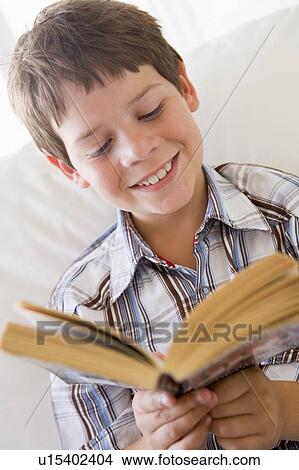 Picture - Young Boy Sitting On A Sofa Reading A Book. Fotosearch