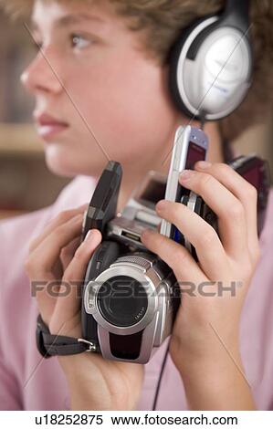 Young boy wearing headphones in bedroom holding many electronic devices View Large Photo Image Stock Photography - Young boy wearing headphones in bedroom holding many electronic devices. Fotosearch
