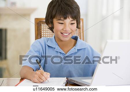 Young boy with laptop doing homework in dining room smiling View Large Photo Image Stock Photography - Young boy with laptop doing homework in dining room smiling. Fotosearch