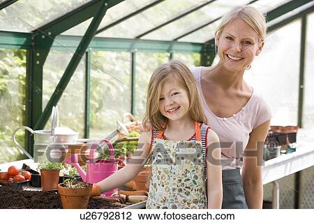 Young girl and woman in greenhouse smiling View Large Photo Image Stock Image - Young girl and woman in greenhouse smiling. Fotosearch