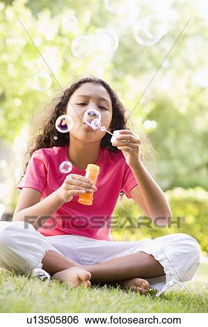Young girl blowing bubbles outdoors View Large Photo Image Stock Photograph - Young girl blowing bubbles outdoors. Fotosearch