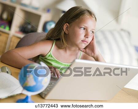 Stock Image - Young Girl Doing Homework On A Laptop. Fotosearch