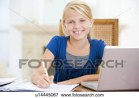 Stock Photo - Young girl with laptop doing homework in dining room smiling. Fotosearch