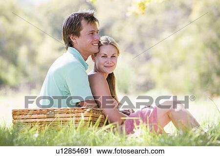 Stock Image - Couple at park having a picnic and smiling. Fotosearch