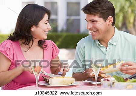 Stock Image - Couple Enjoying A Barbequed Meal In The Garden. Fotosearch