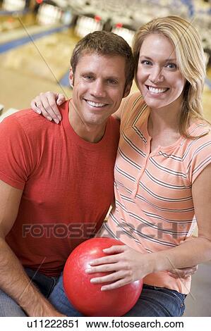 Couple in bowling alley holding ball and smiling View Large Photo Image Stock Image - Couple in bowling alley holding ball and smiling. Fotosearch