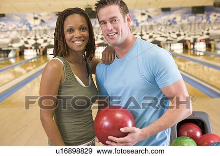 Couple in bowling alley holding ball and smiling View Large Photo Image Stock Photo - Couple in bowling alley holding ball and smiling. Fotosearch