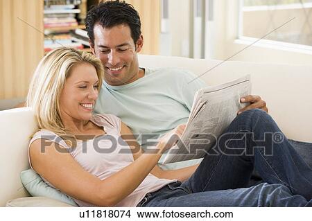 Couple in living room reading newspaper and smiling View Large Photo Image Picture - Couple in living room reading newspaper and smiling. Fotosearch