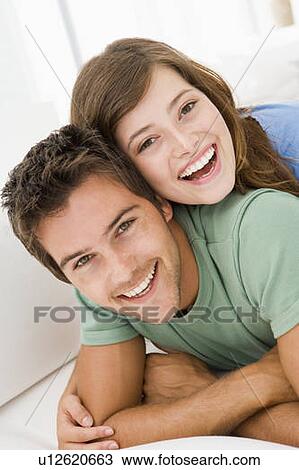 Stock Image - Couple in living room smiling. Fotosearch