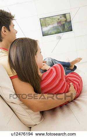 Couple in living room watching television View Large Photo Image Picture - Couple in living room watching television. Fotosearch