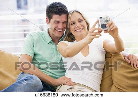 Couple in living room with digital camera smiling View Large Photo Image Stock Image - Couple in living room with digital camera smiling. Fotosearch