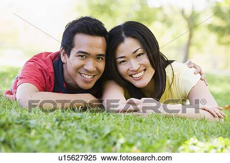 Stock Photography - Couple lying outdoors smiling. Fotosearch