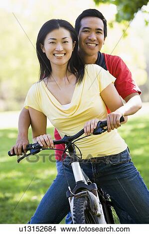 Couple on a bike outdoors smiling View Large Photo Image Picture - Couple on a bike outdoors smiling. Fotosearch