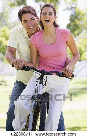 Couple on a bike outdoors smiling View Large Photo Image Stock Image - Couple on a bike outdoors smiling. Fotosearch