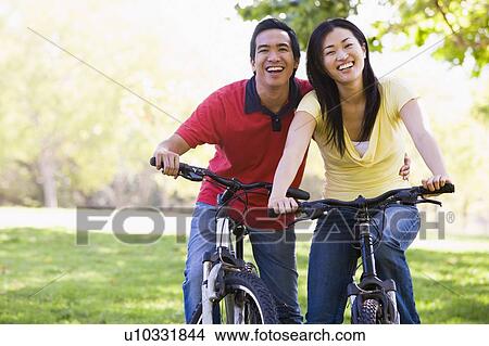 Couple on bikes outdoors smiling View Large Photo Image Picture - Couple on bikes outdoors smiling. Fotosearch