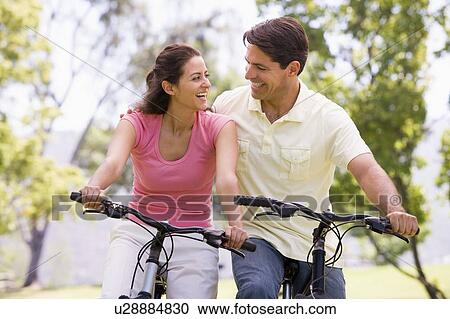Couple on bikes outdoors smiling View Large Photo Image Stock Image - Couple on bikes outdoors smiling. Fotosearch