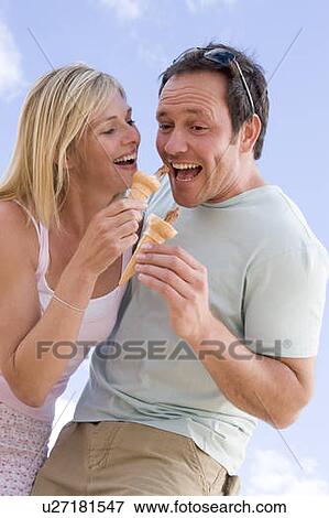 Couple outdoors eating ice cream and smiling View Large Photo Image Stock Photo - Couple outdoors eating ice cream and smiling. Fotosearch