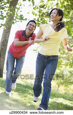 Picture - Couple running and being playful outdoors smiling. Fotosearch
