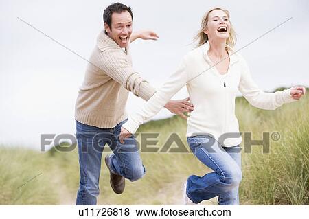 Couple running at beach smiling View Large Photo Image Stock Photo - Couple running at beach smiling. Fotosearch