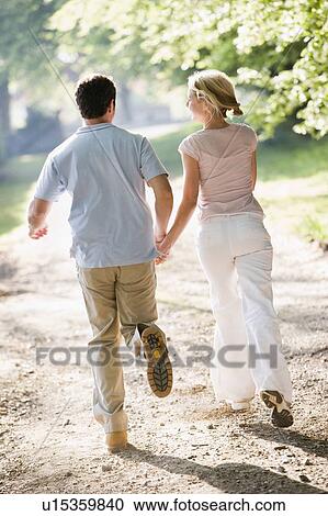 Couple running outdoors holding hands View Large Photo Image Stock Image - Couple running outdoors holding hands. Fotosearch