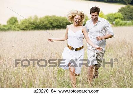 Picture - Couple running outdoors smiling. Fotosearch
