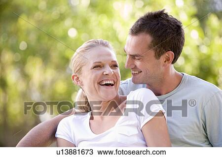 Stock Image - Couple sitting outdoors laughing. Fotosearch