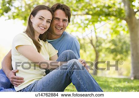 Picture - Couple sitting outdoors smiling. Fotosearch