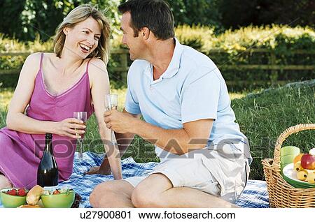 Couple sitting outdoors with picnic smiling View Large Photo Image Stock Image - Couple sitting outdoors with picnic smiling. Fotosearch