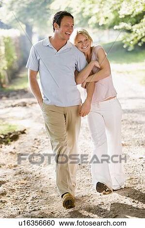 Couple walking outdoors arm in arm smiling View Large Photo Image Stock Image - Couple walking outdoors arm in arm smiling. Fotosearch