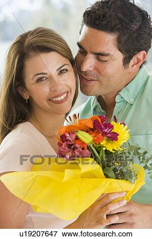 Stock Photo - Husband and wife holding flowers and smiling. Fotosearch