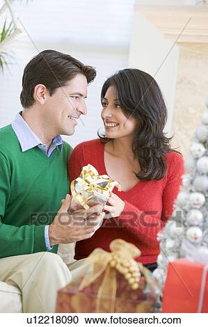 Stock Image - Husband Surprising Wife With Christmas Present. Fotosearch